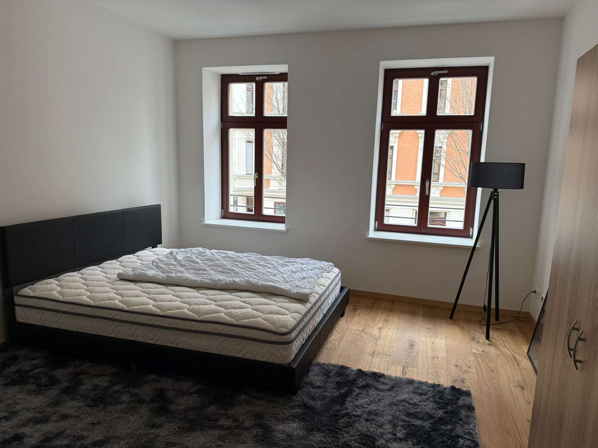 geräumiges Schlafzimmer mit Bett, Schrank, Lampe und Teppich