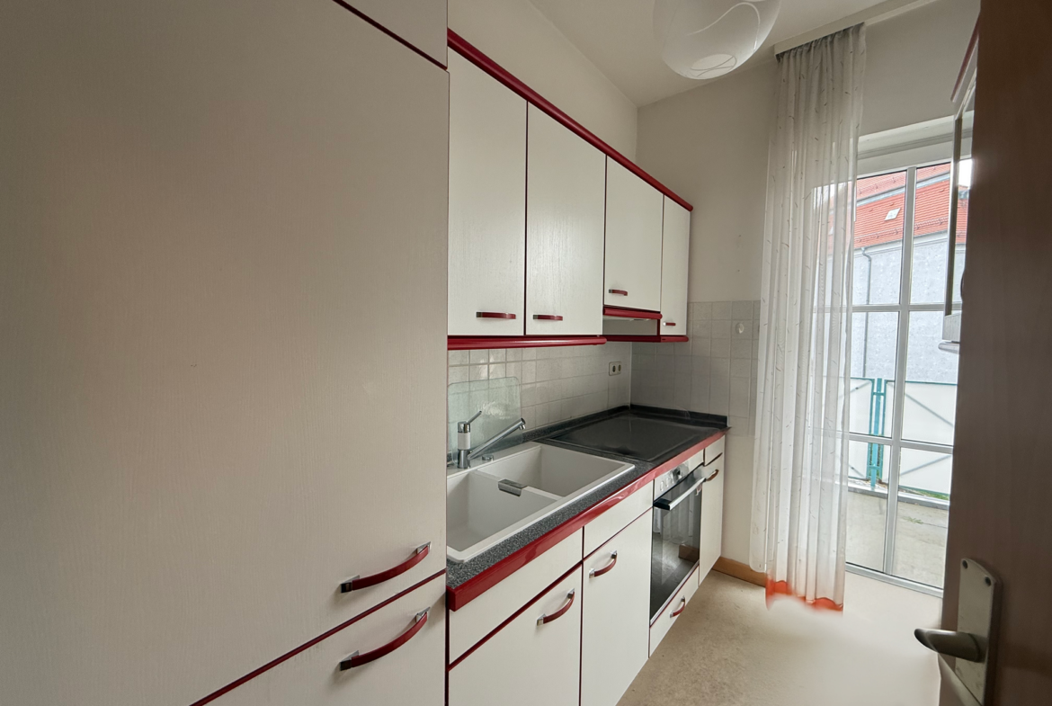 Einbauküche mit Kühlschrank, Herd, Ofen und Zugang zum Balkon