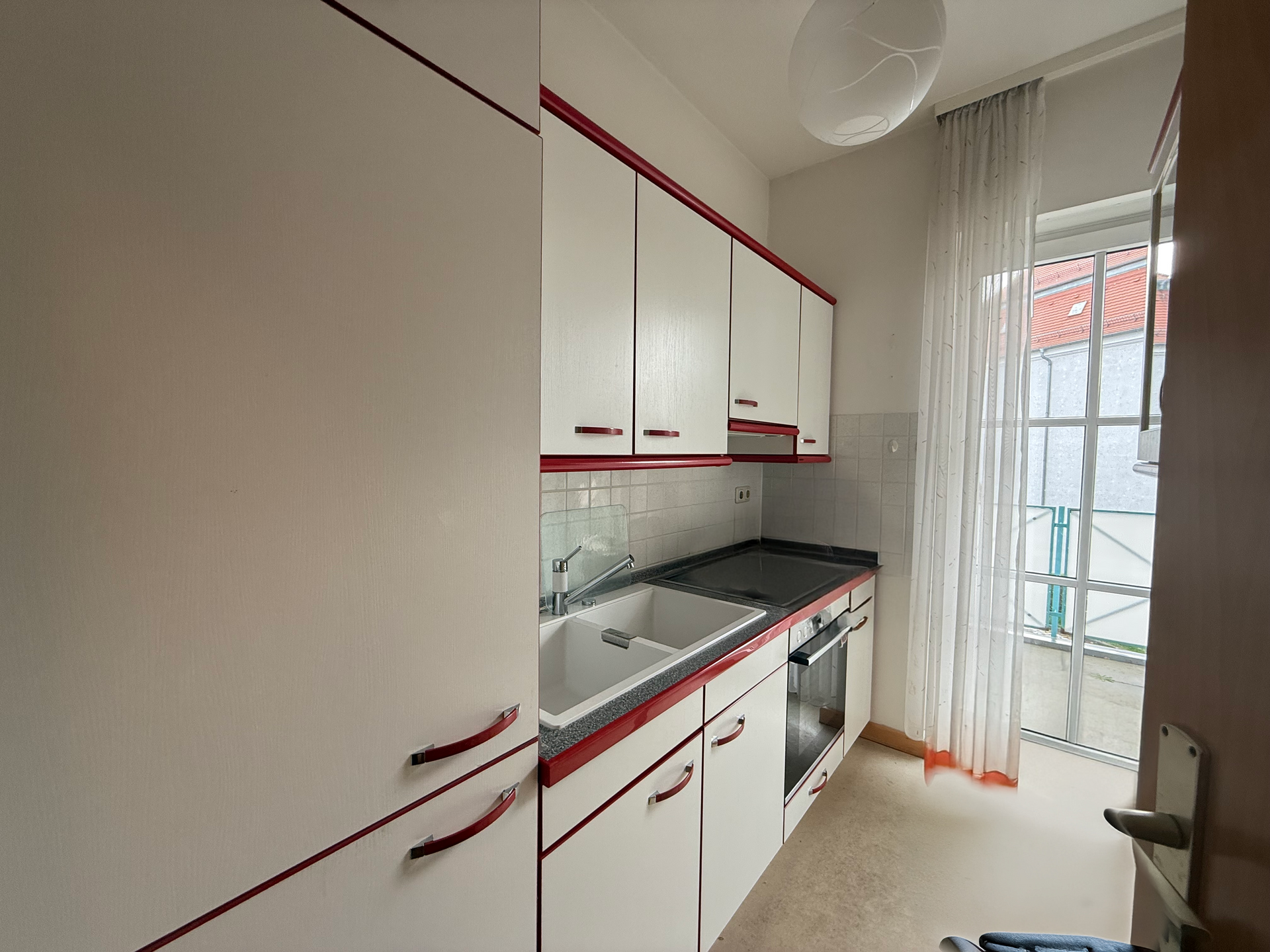 Einbauküche mit Kühlschrank, Herd, Ofen und Zugang zum Balkon