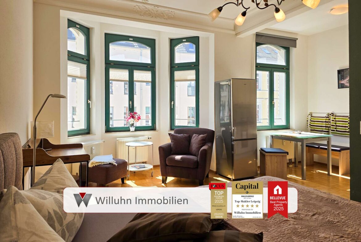 Eine helle, moderne Wohnung mit großen, grün gestrichenen Fenstern, Holzböden und modernen Möbeln. Die Logos und Auszeichnungen von Willuhn Immobilien sind am unteren Bildrand eingeblendet.