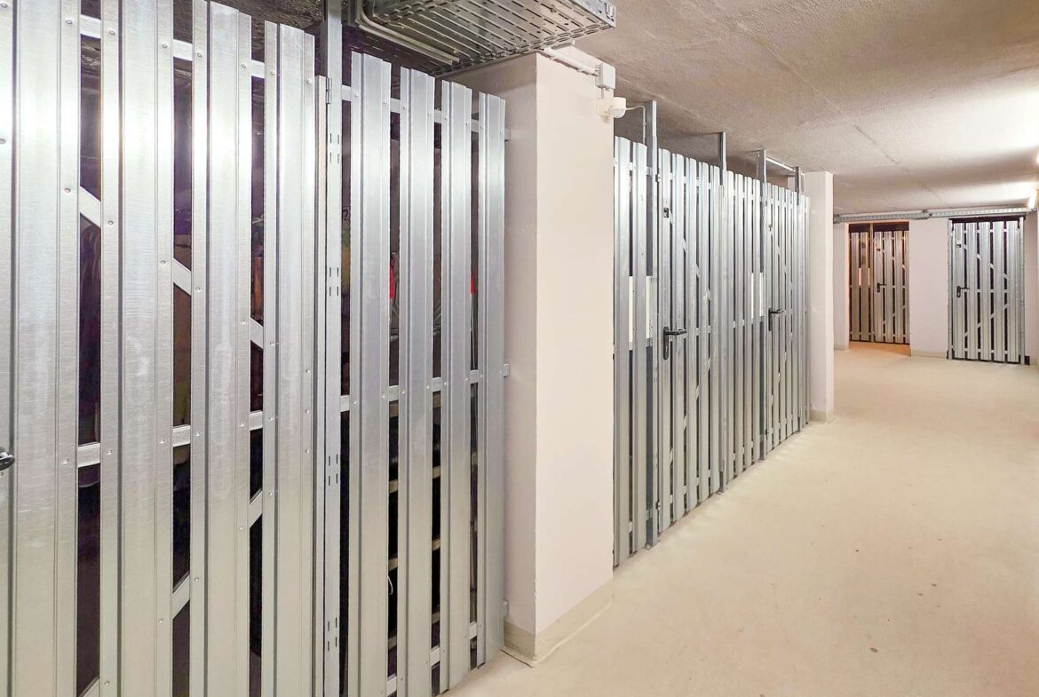 Long hallway of a storage facility with silver metal lockers lining the walls on both sides.