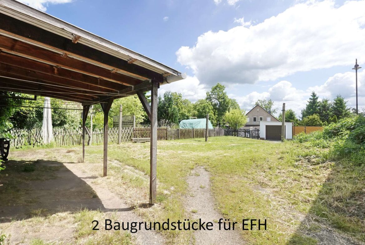 Backyard scene with a wooden carport on the left, a grassy area and fence, and a house in the distance; overlay text advertises two building plots for single-family homes.