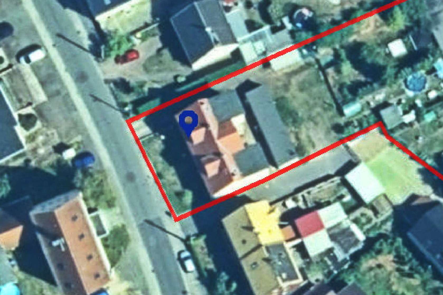 Aerial view of a house with red boundary lines marking its property, blue location pin at the center.