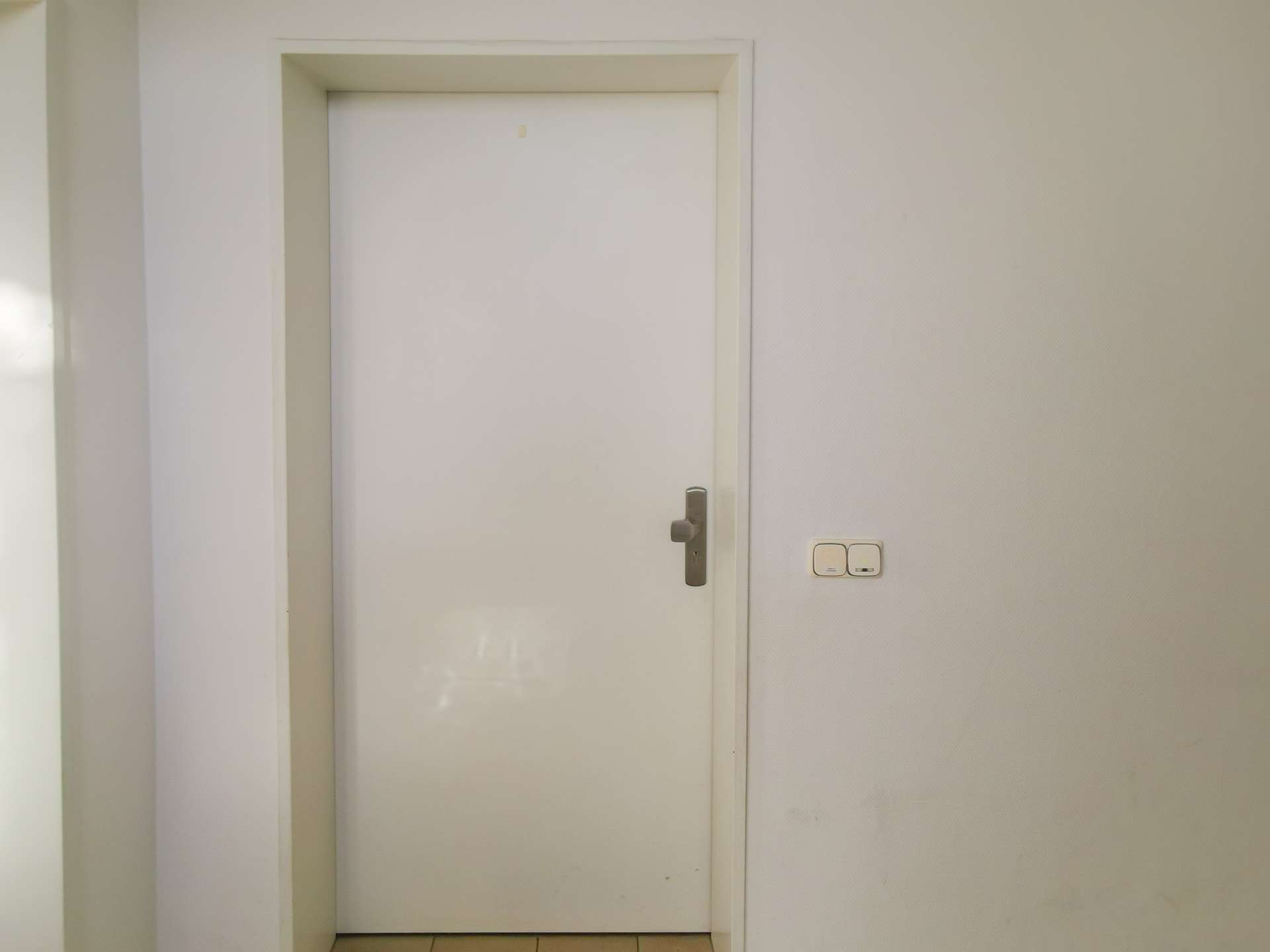 White interior door in a narrow hallway with a light switch on the wall to the right