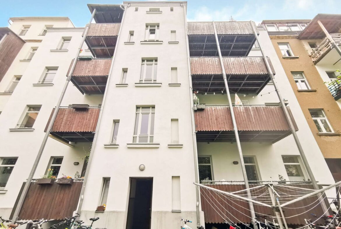 Courtyard view of a white apartment building with brown wooden balconies and bicycles in the foreground