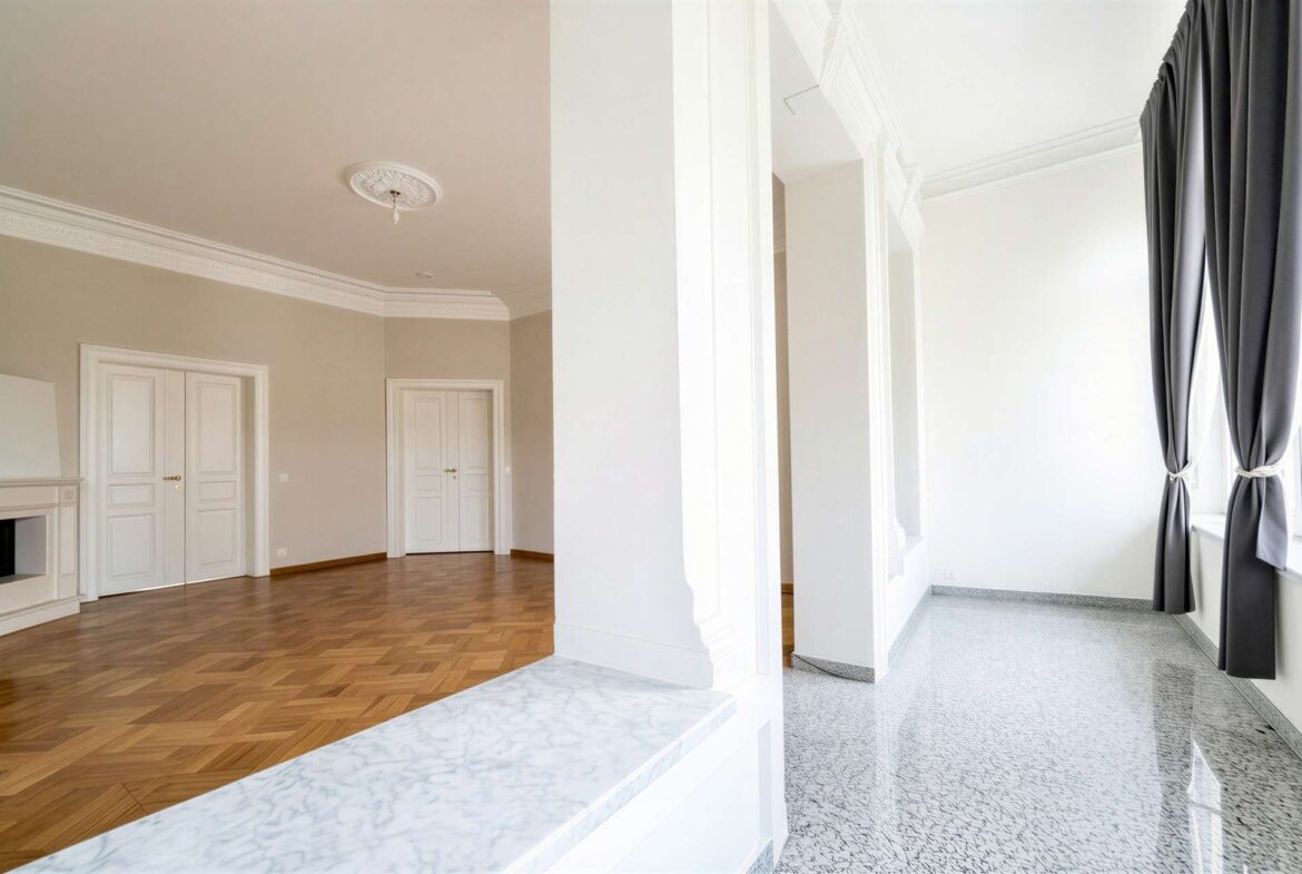 Spacious interior: left room with parquet floor and white doors; right, bright space with grey curtains.