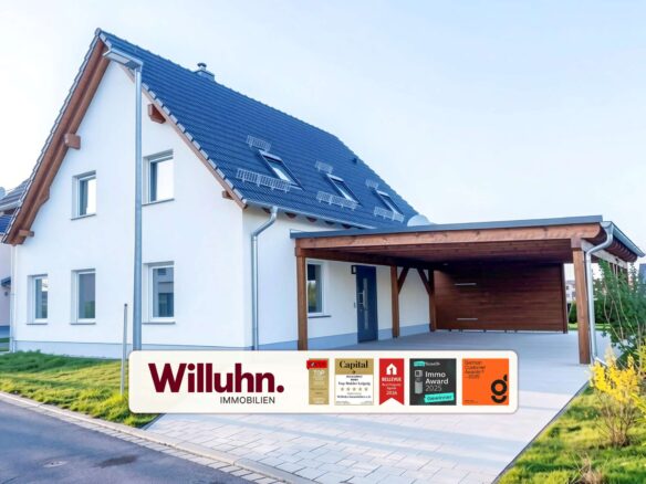 Modern white two-story house with a blue tiled pitched roof and a wooden-carport, branding for Willuhn Immobilien on a banner in the foreground.