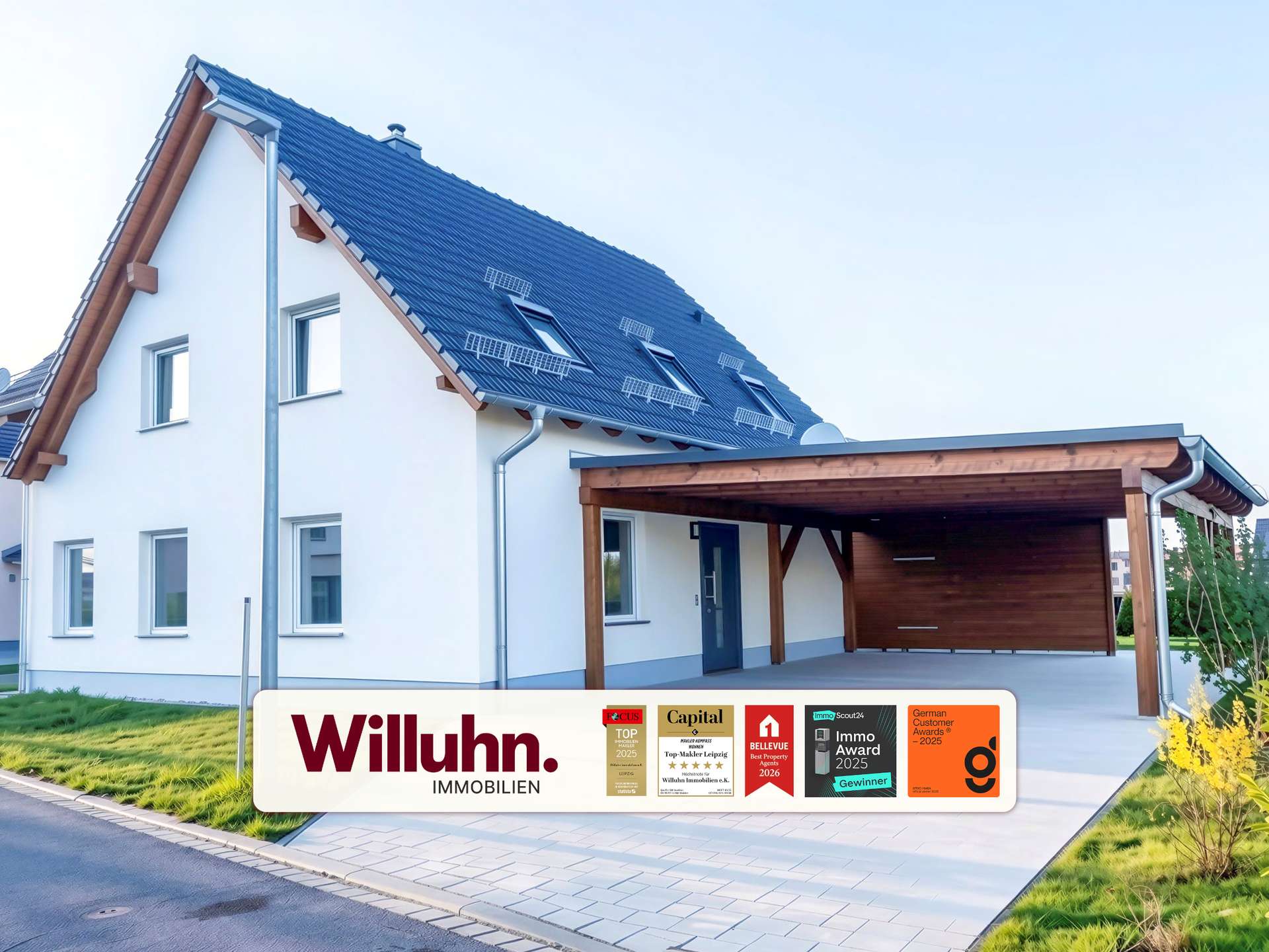 Modern white two-story house with a blue tiled pitched roof and a wooden-carport, branding for Willuhn Immobilien on a banner in the foreground.