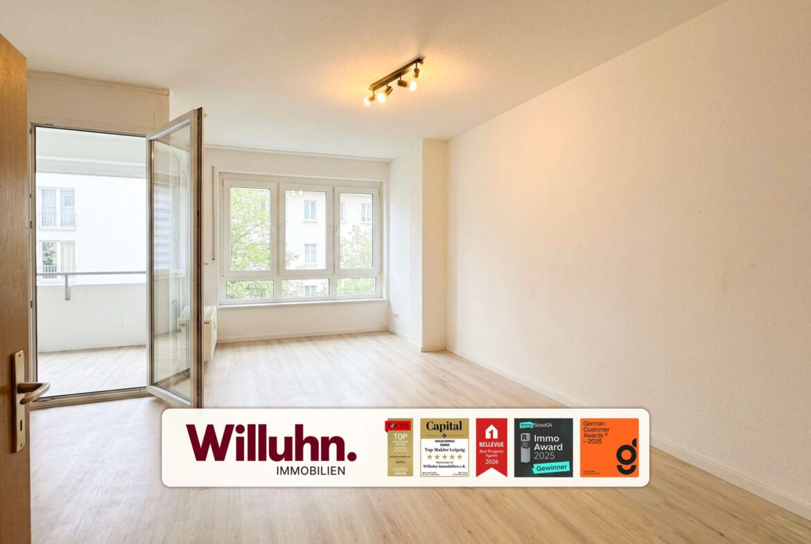 Bright, empty living room with large windows and an open glass balcony door; Real estate banner reads 'Willuhn Immobilien' with award badges along the bottom edge.
