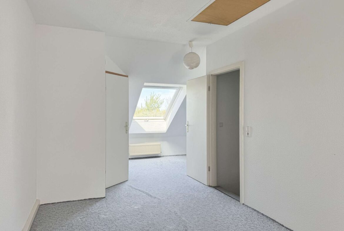 Bright white hallway with two open doors at the far end, a skylight and a hanging round paper lantern, pale patterned carpet.