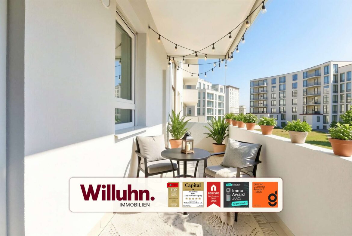 Sunny apartment balcony with a small table, two chairs, string lights, and potted plants; a Willuhn Immobilien banner is visible.