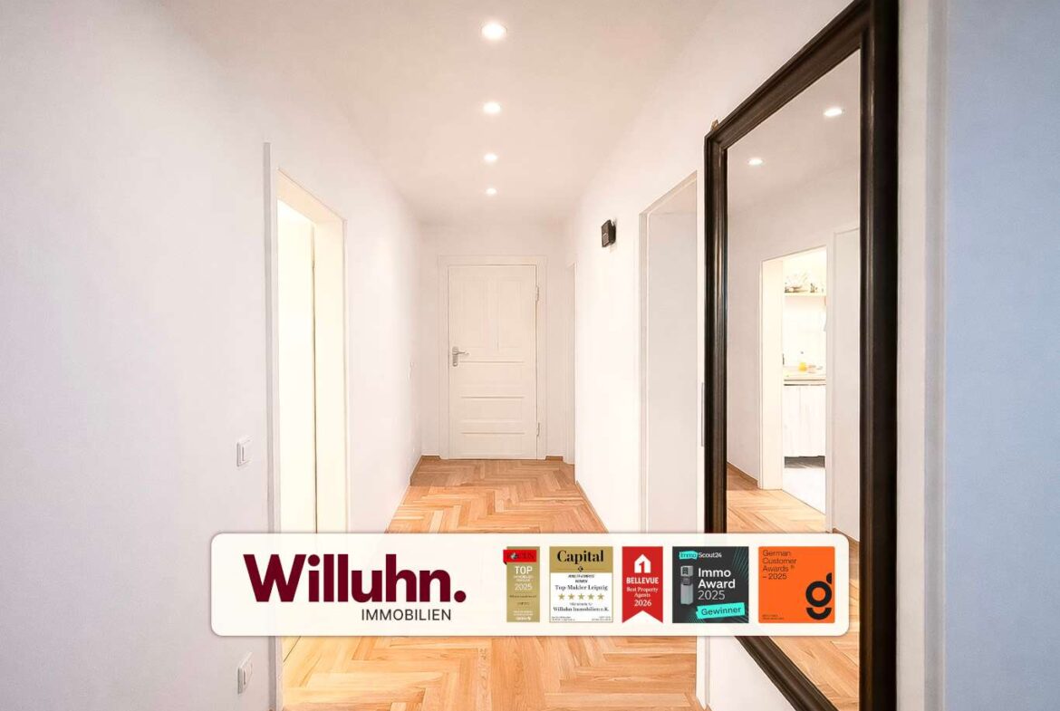 Bright white hallway with a herringbone wooden floor, end door, and a large dark-framed mirror on the right; branding and award badges across the bottom.