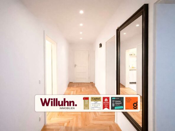 Bright white hallway with a herringbone wooden floor, end door, and a large dark-framed mirror on the right; branding and award badges across the bottom.