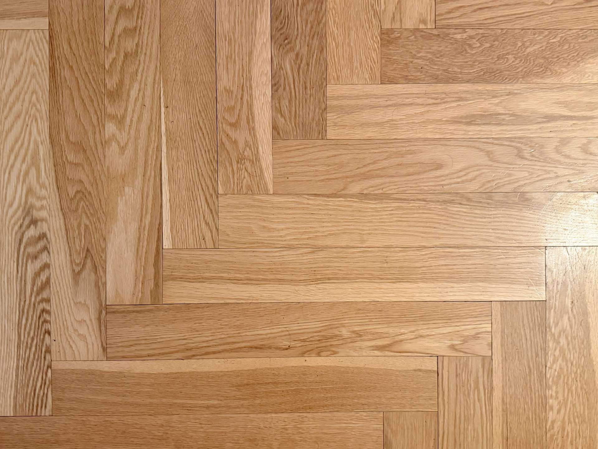 Light oak parquet floor with a herringbone-style rectangular plank pattern and warm honey tones Amidst wood grain details?