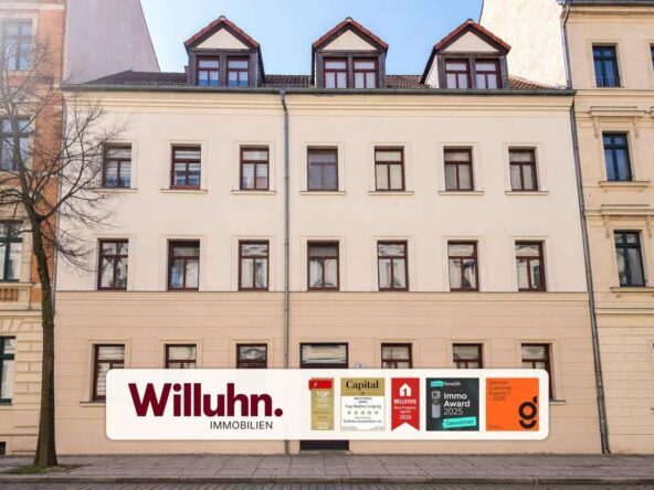 White real estate banner on a beige building that reads 'Willuhn. Immobilien' with multiple award plaques along the bottom edge, at street level.