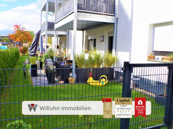 Exposed fenced courtyard of a modern apartment building with outdoor seating, potted plants, and yellow pool float near the gate, signs for a real estate agency visible on the fence