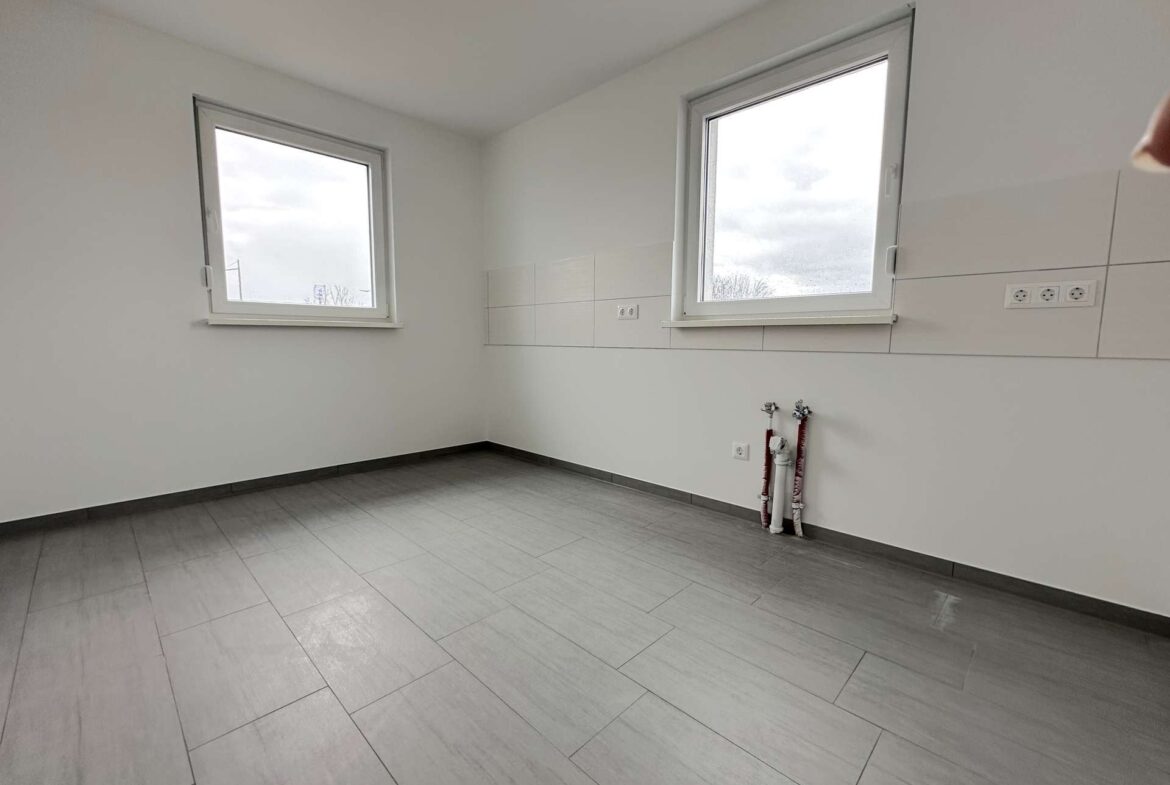 Unfurnished room with two windows, light gray floor tiles, and exposed plumbing near the wall.