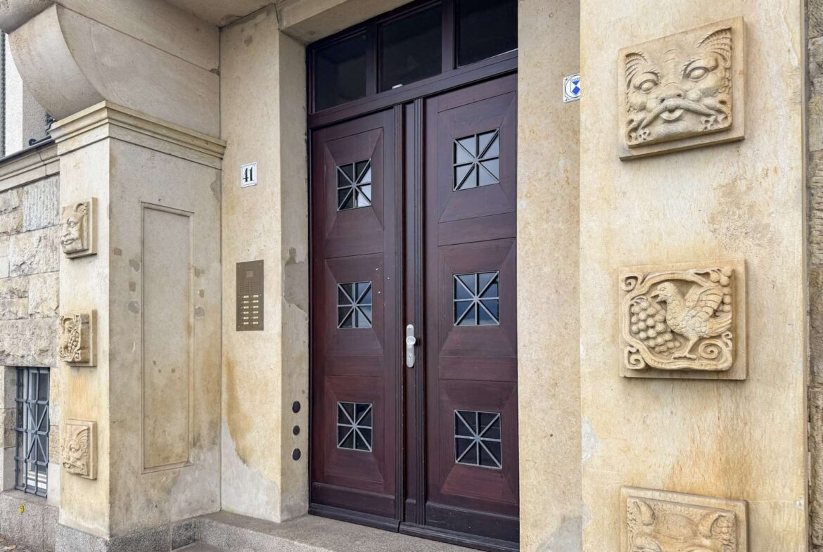 Beige stone building entry with dark wooden double doors and decorative square-window panes; house number 41 on the wall.