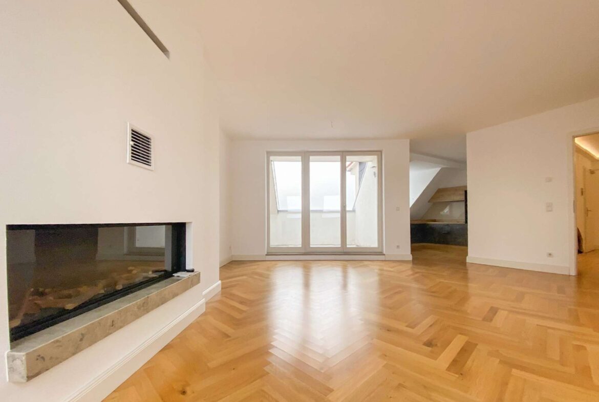 Empty modern living room with a herringbone wooden floor, left-side fireplace, and large glass doors to a balcony at the back center.