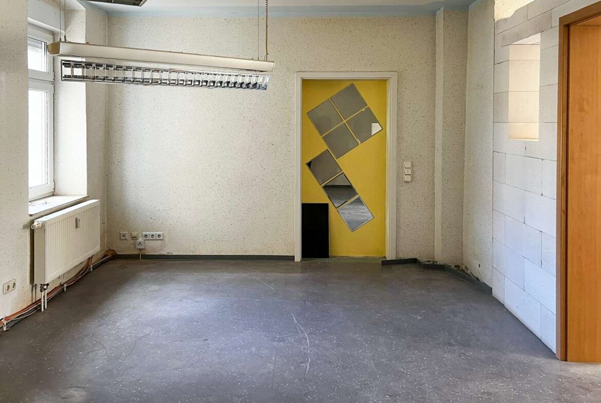 Empty unfinished room with a yellow door featuring diagonal reflective panels as wall art.