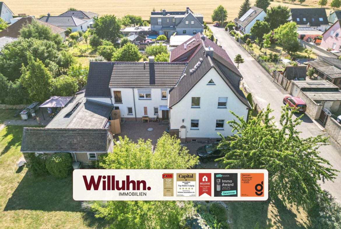 Aerial view of a suburban neighborhood with white houses, red-tiled roofs, and plenty of trees; a large Willuhn Immobilien banner runs across the bottom edge.