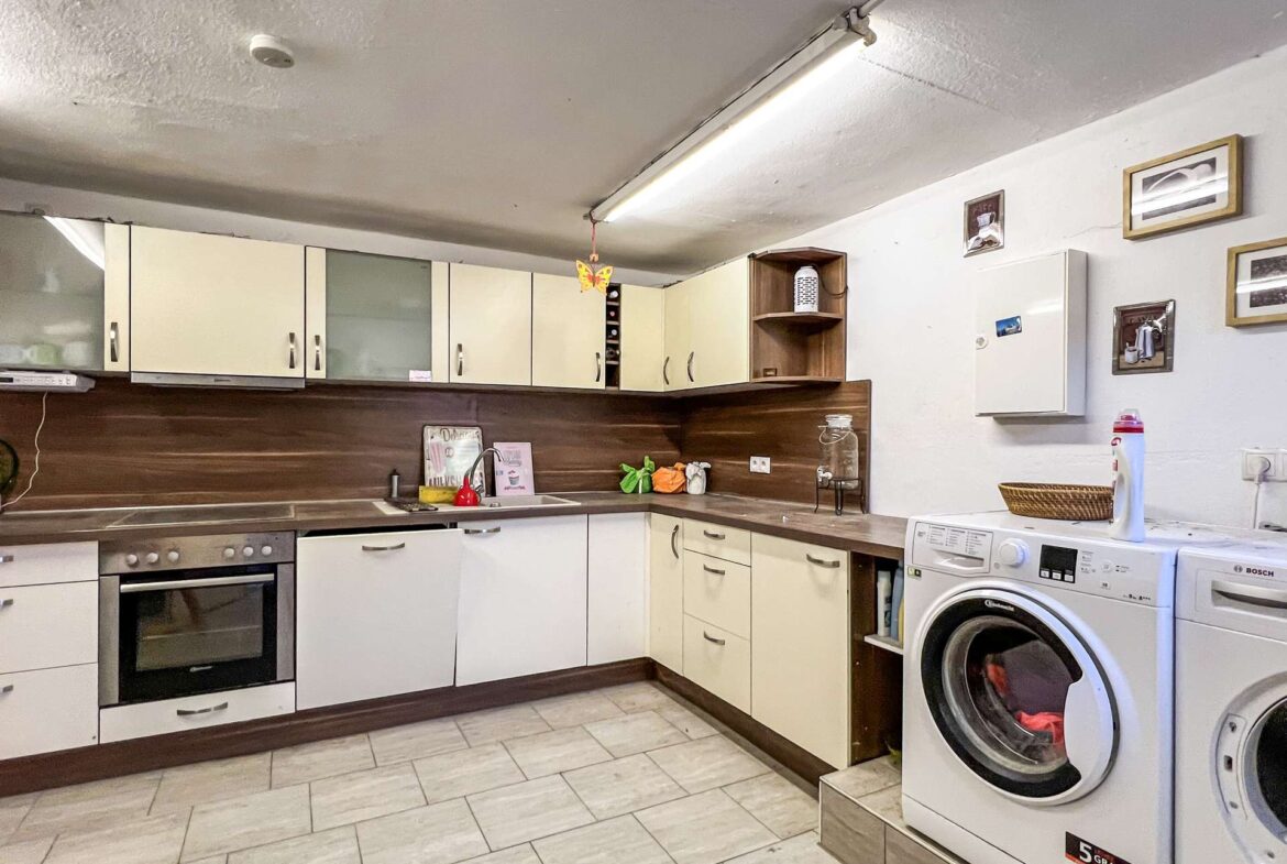 Modern kitchen with cream cabinets, a sink, and a stacked washer/dryer to the right.