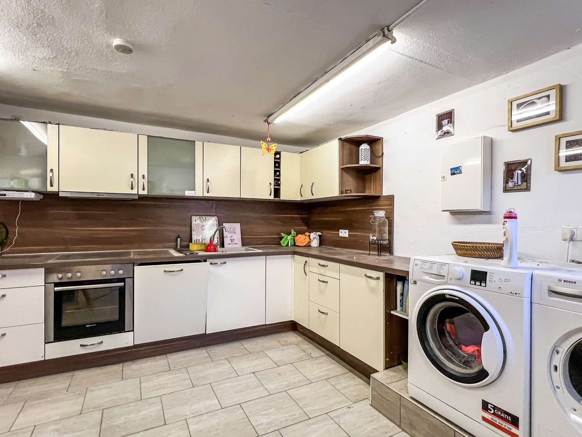 Modern kitchen with cream cabinets, a sink, and a stacked washer/dryer to the right.