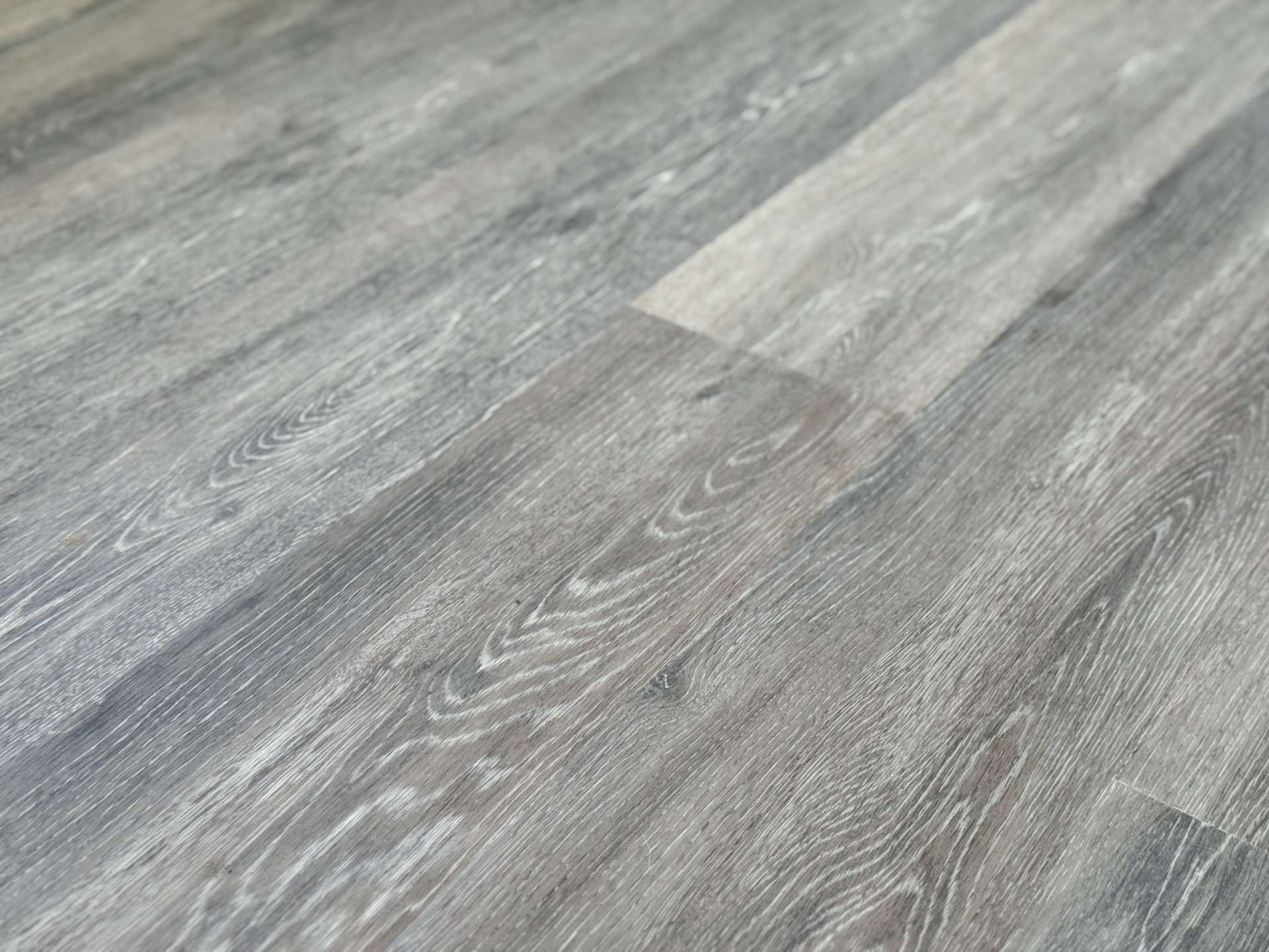 Close-up of weathered gray wooden floorboards with visible grain patterns and subtle scratches.