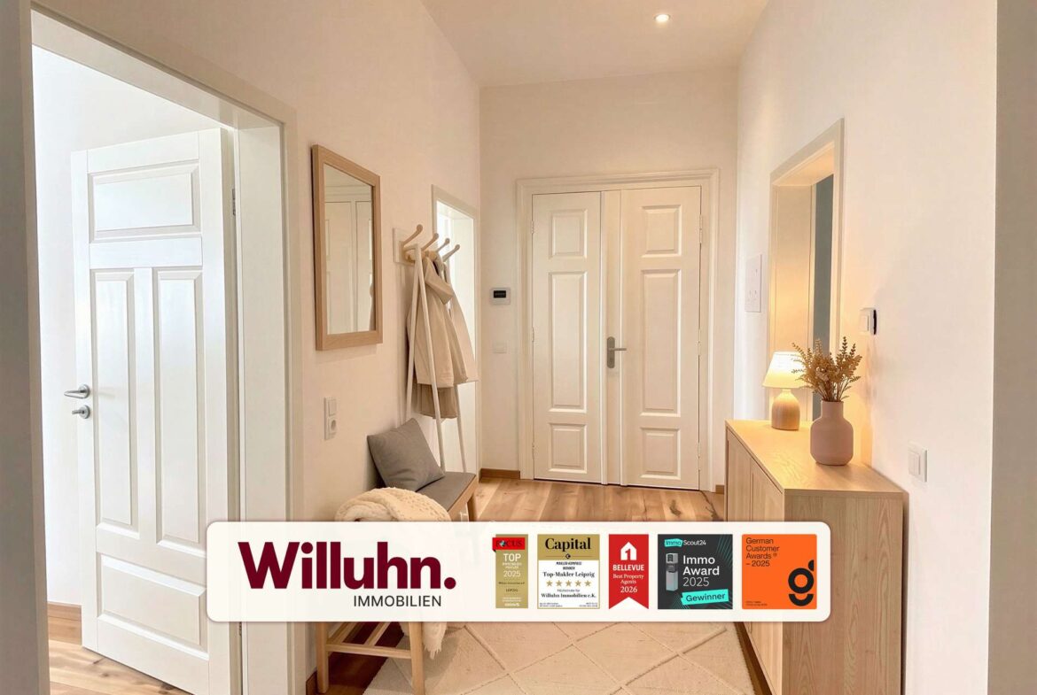 Bright entry hallway with white doors, a coat rack and bench along the left wall, and a wooden console with a vase on the right; a Willuhn Immobilien banner at the bottom.