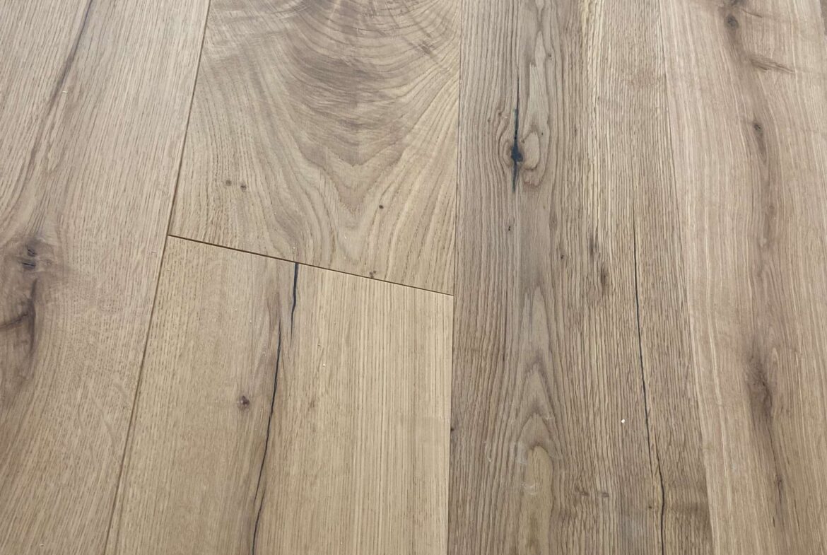 Wooden floor with wide natural-grain planks, light brown color and visible knots.