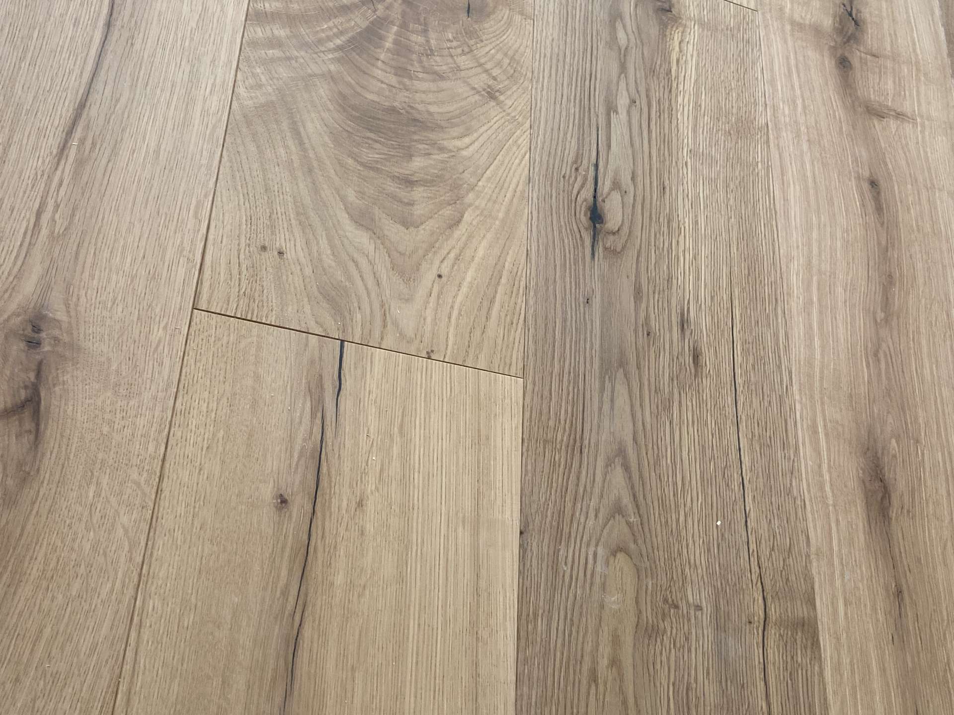 Wooden floor with wide natural-grain planks, light brown color and visible knots.