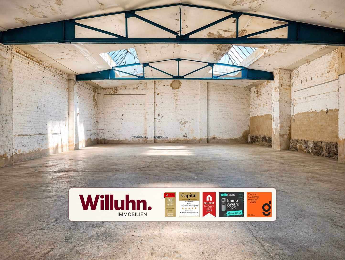 Empty industrial warehouse interior with white brick walls, blue steel trusses, and skylights; a Willuhn Immobilien banner along the floor.