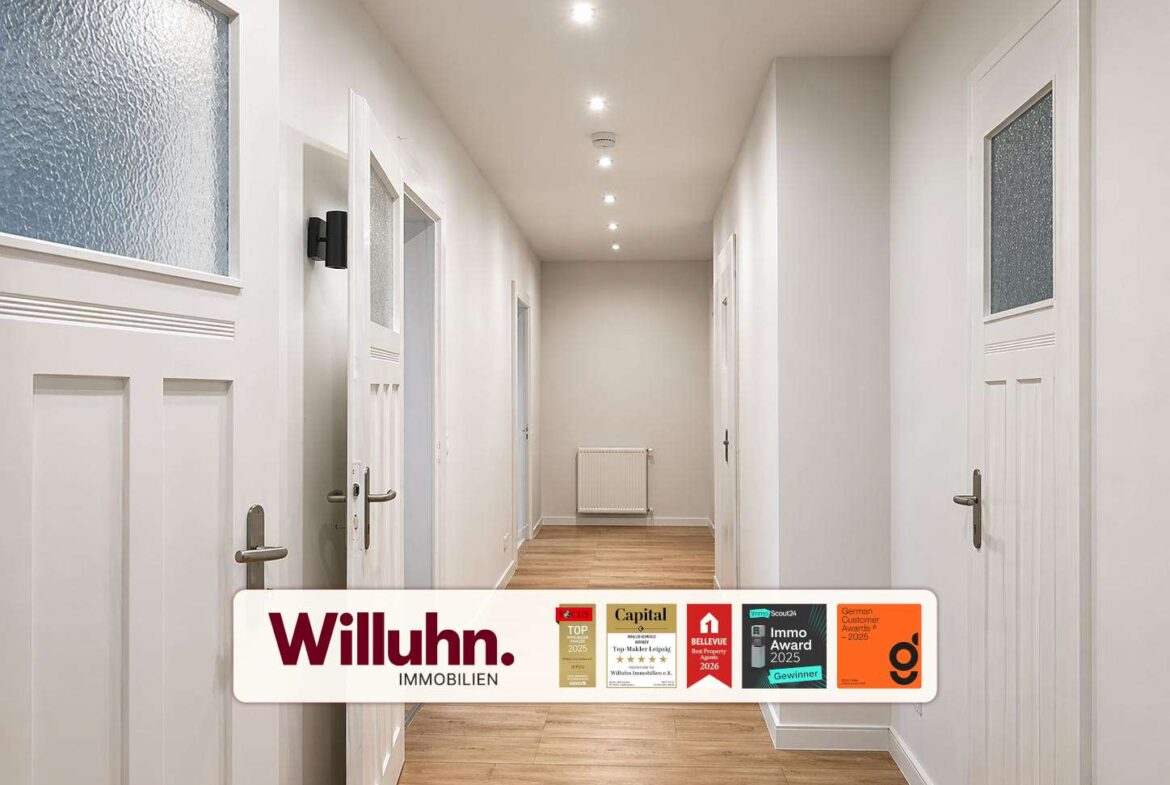 Bright hallway with white doors, light wood floor, and recessed ceiling lights; radiator at the far end.