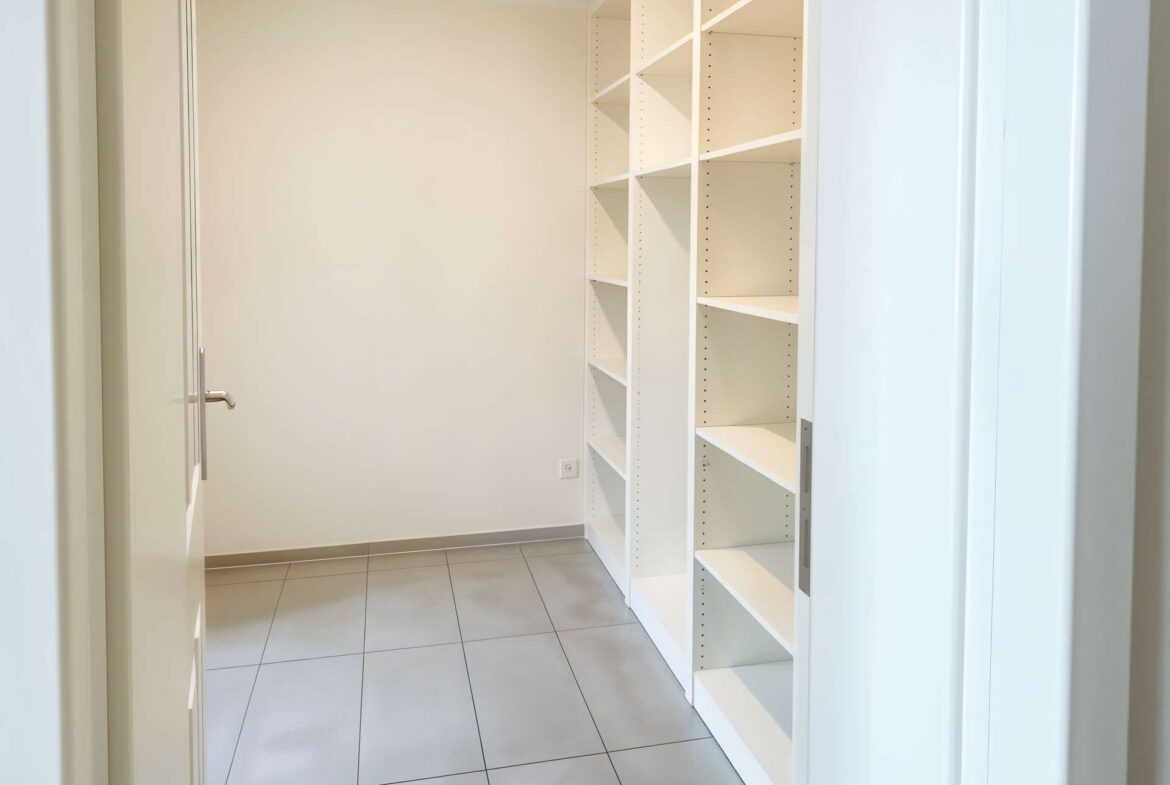 Tall white shelving unit with adjustable shelves along a beige wall in a narrow storage closet, empty and ready for use()