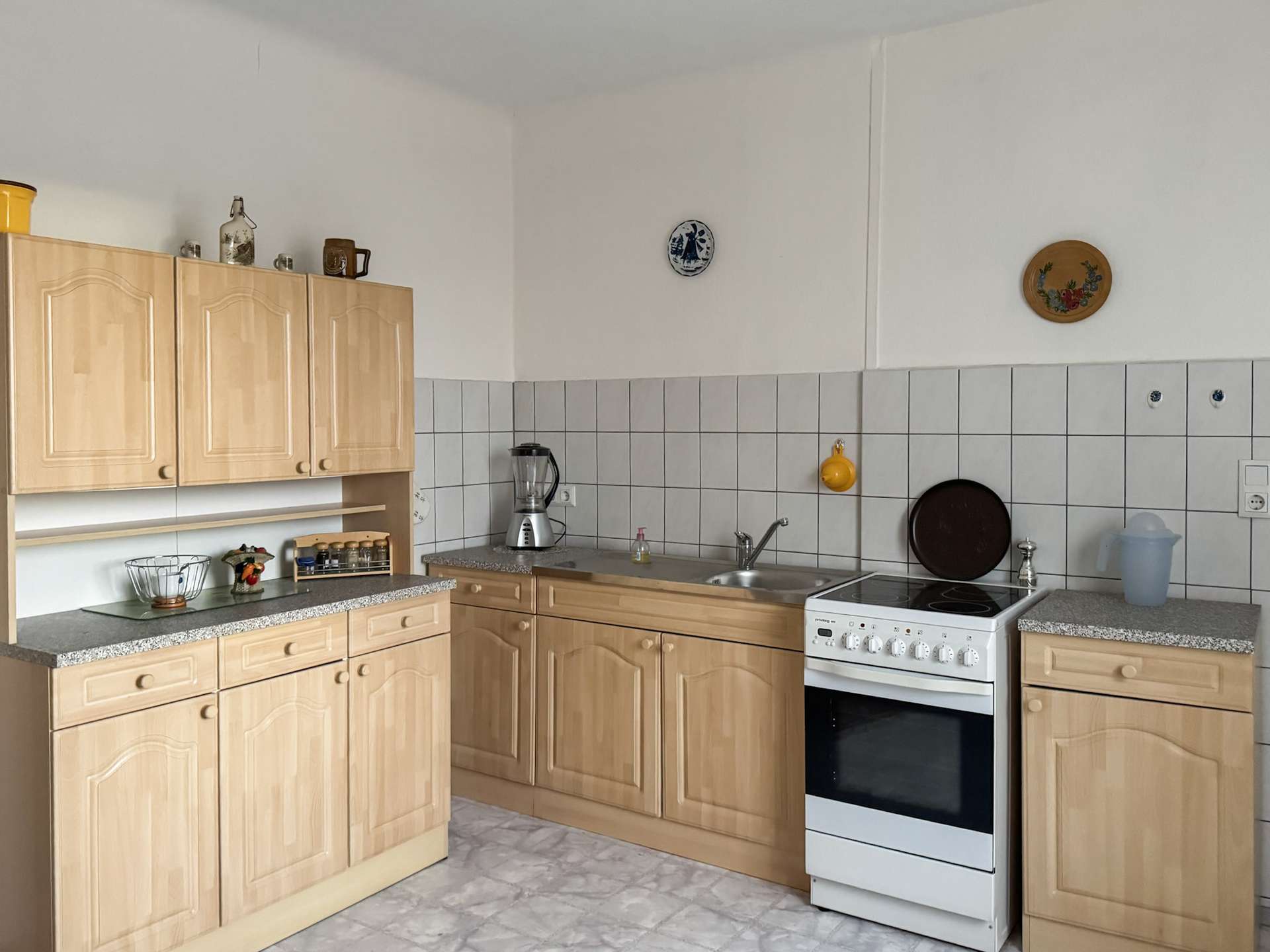 Kitchen with light wood cabinets, tiled backsplash, sink, and a white oven set in a U-shaped counter layout