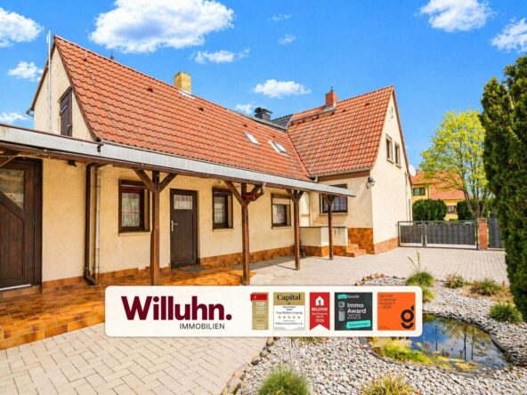 Front view of a beige house with red-tiled roof and a long covered walkway, Willuhn Immobilien banner across the bottom.