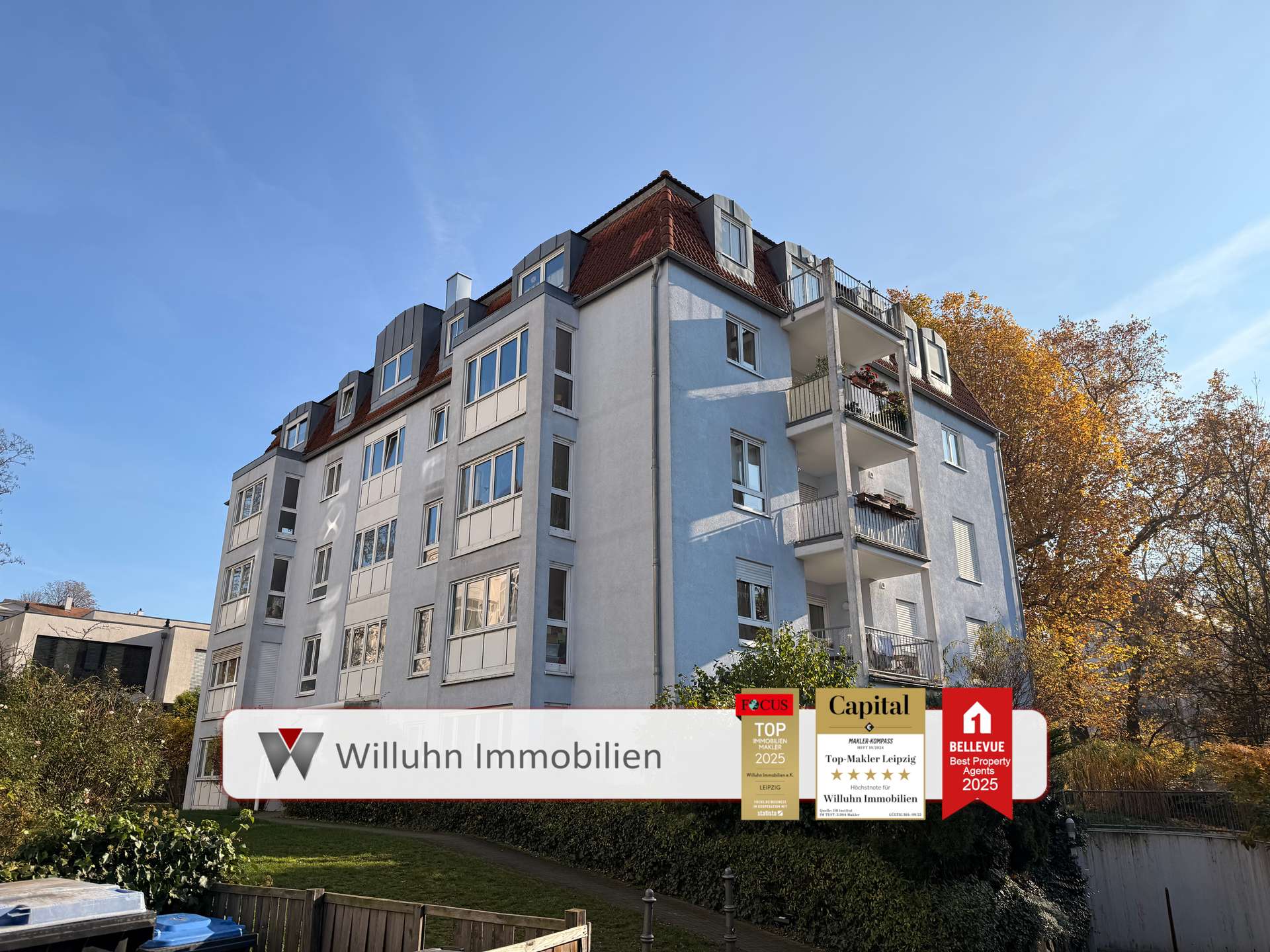 Five-story apartment building with blue and white facade under a clear sky; promotional banners for real estate agency at the bottom.