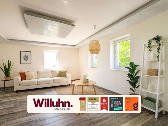 Bright living room with a white sofa, round wooden coffee table, and tall green plants; Willuhn Immobilien branding banner at the bottom.