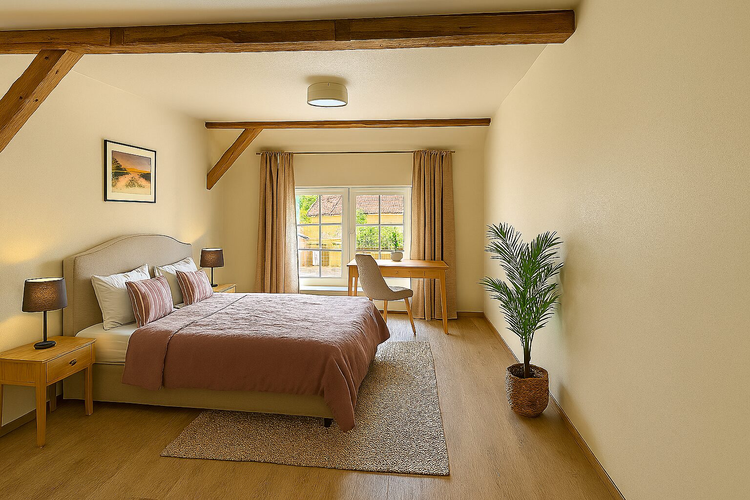 Cozy bedroom with a large bed, two nightstands and lamps, beige walls, and exposed wooden ceiling beams. A desk sits by the window with curtains behind it and a potted plant nearby.