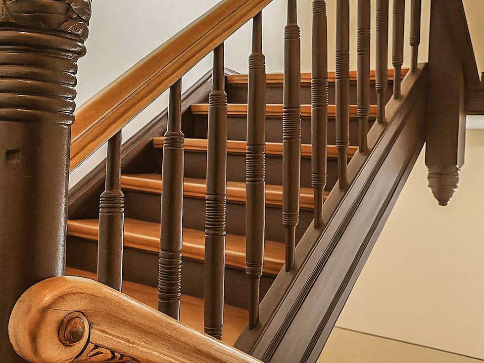 Wooden staircase with turned balusters and a curved handrail in warm brown tones.