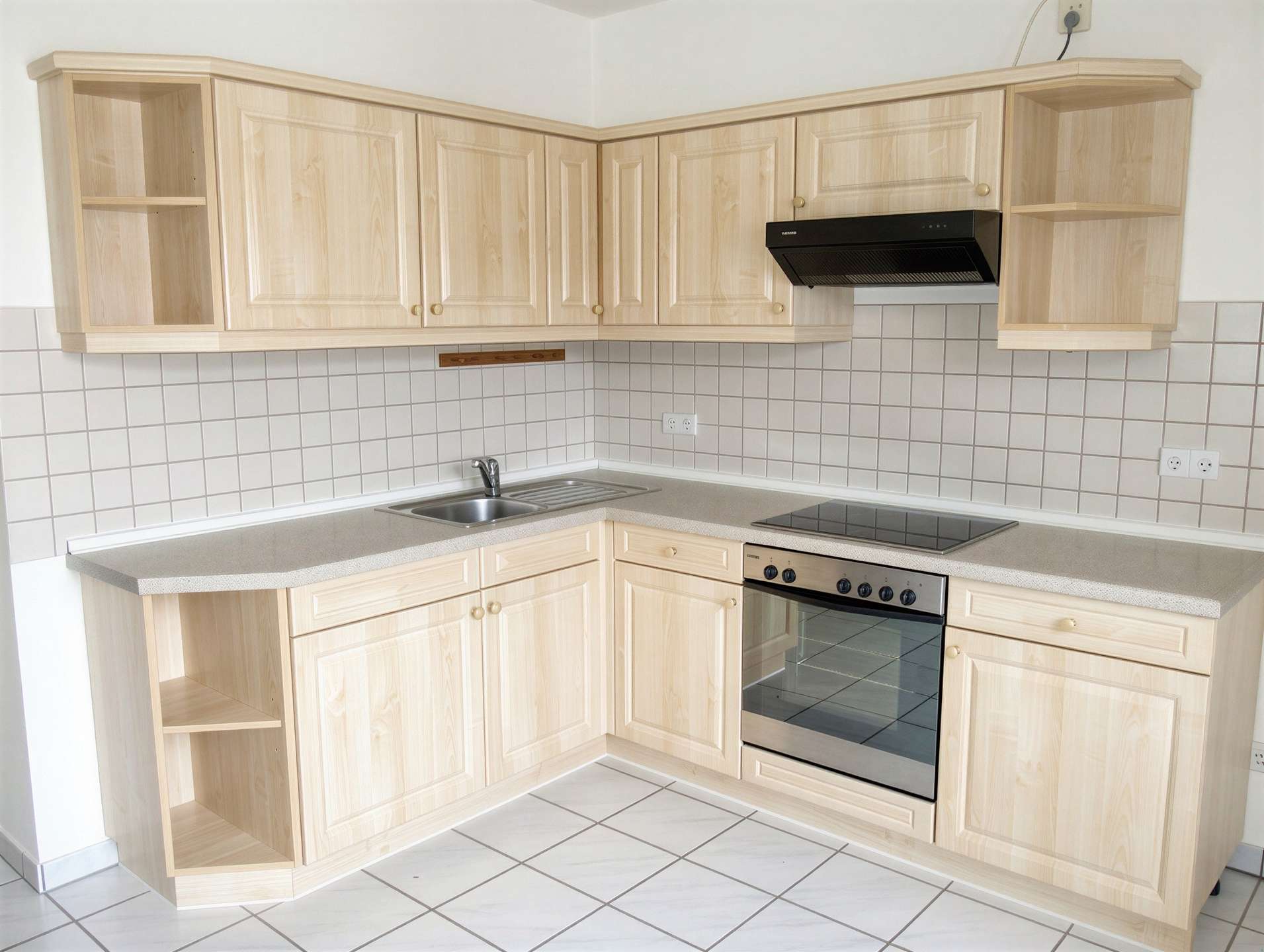 L-shaped kitchen with light wood cabinets, open shelves, and a black range hood above a stove and oven
