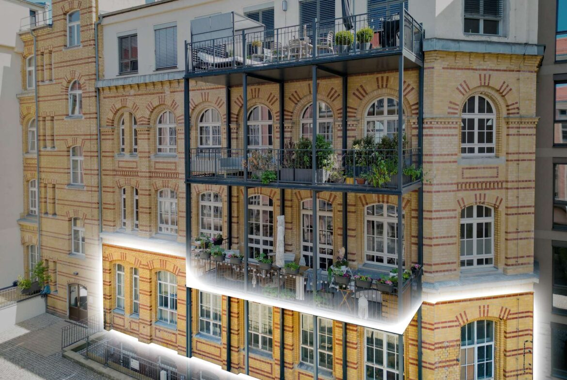 Brick apartment building with arched windows and three-tier metal balconies loaded with potted plants and furniture on each level, urban setting