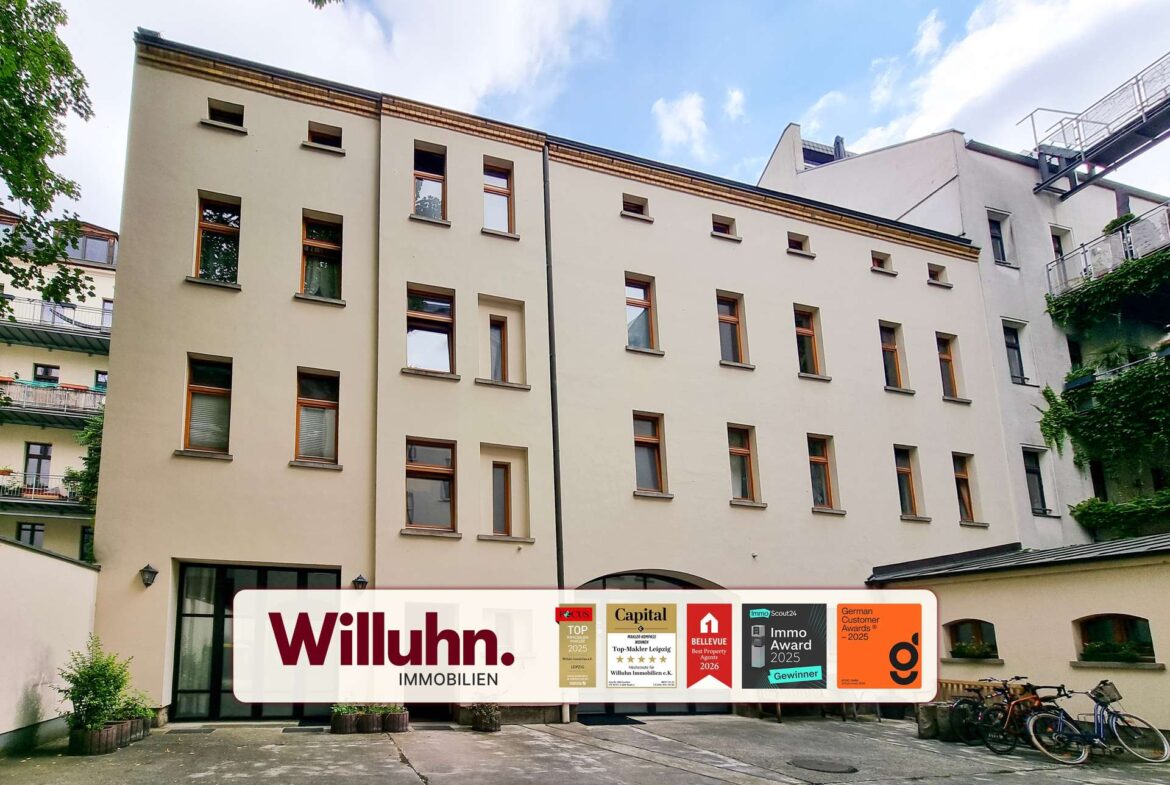 Beige multi-story building with many windows and a large Willuhn Immobilien banner across the ground-floor façade.
