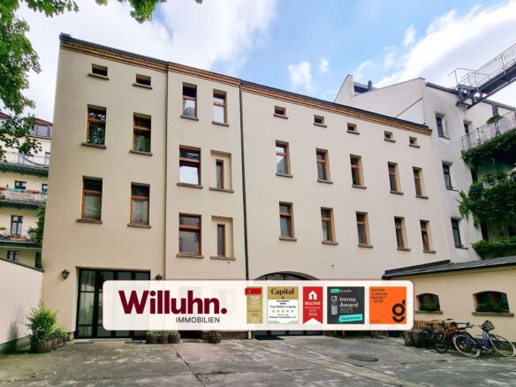 Beige multi-story building with many windows and a large Willuhn Immobilien banner across the ground-floor façade.