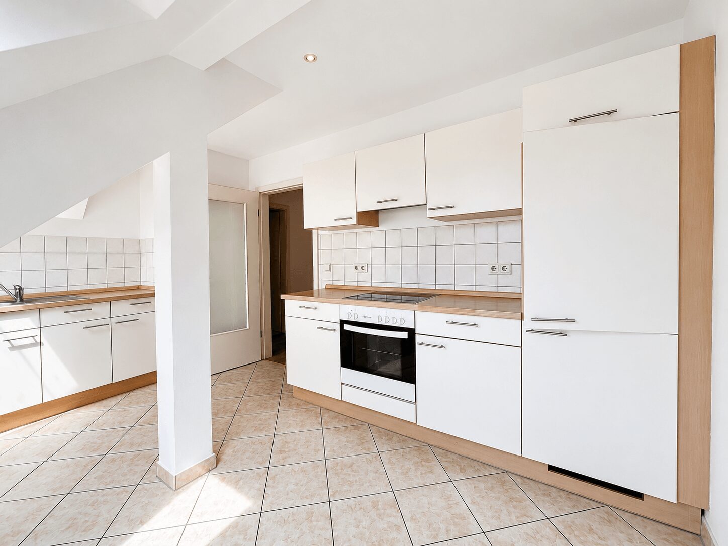 Bright white kitchen with wooden countertops, white cabinets, and a built-in oven along the wall on the right side.