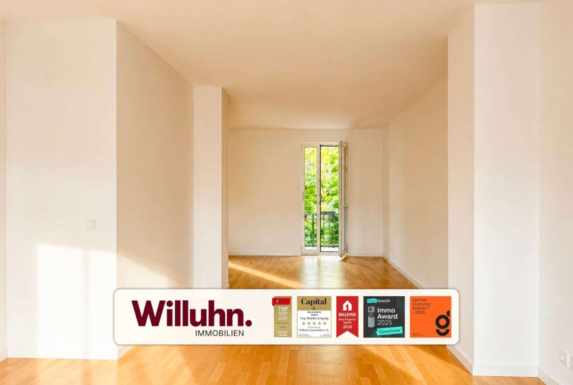 Bright empty living room with light wood floor and a balcony door at the far end; Willuhn Immobilien ad bar at the bottom.