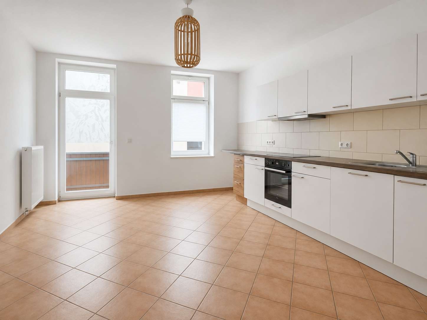 Bright modern kitchen with white cabinets, tiled backsplash, built-in oven, and a door to a balcony/balcony railing.