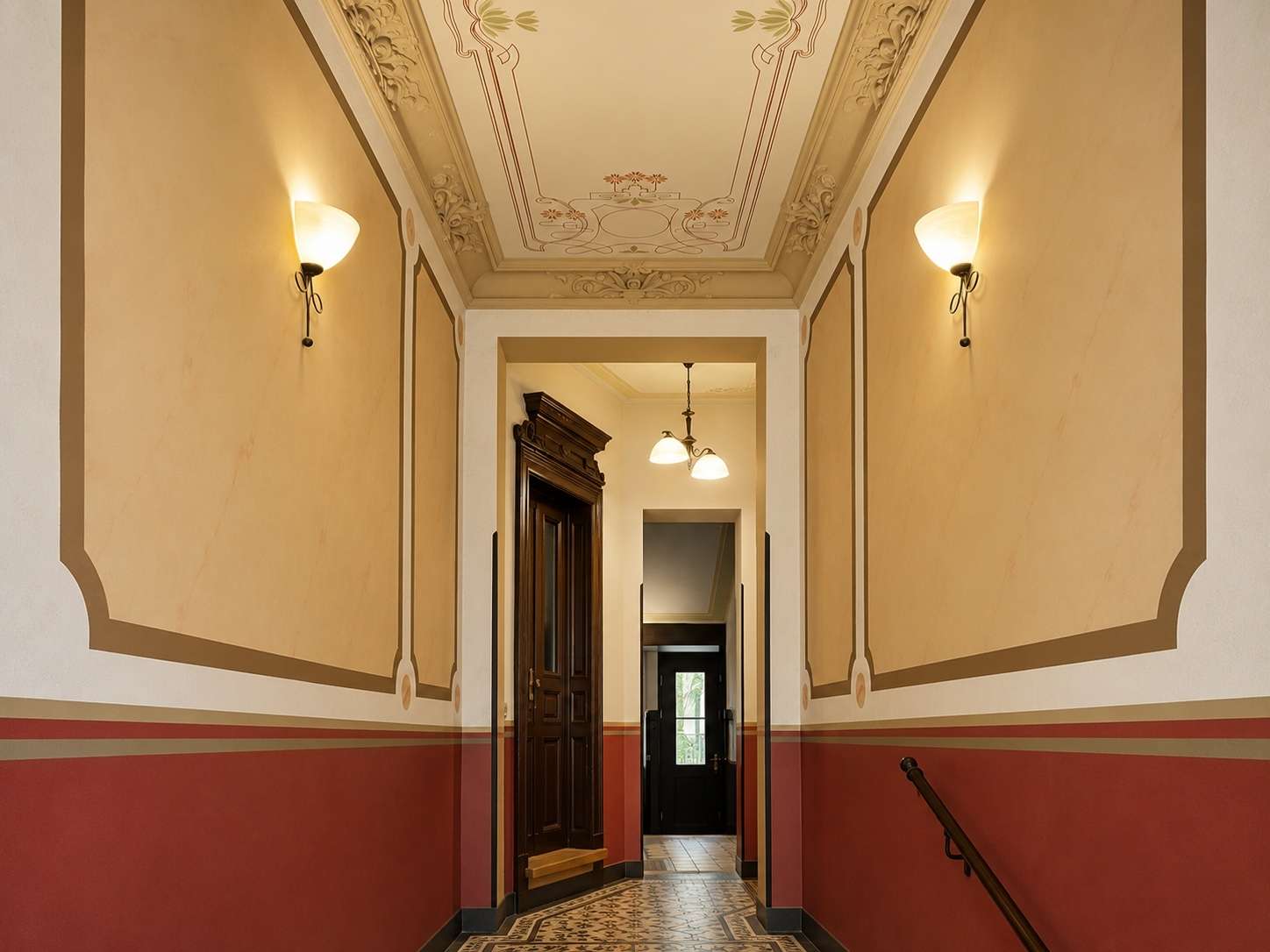 Elegant vintage hallway with ornate ceiling molding and warm beige walls, leading to a dark wooden door at the end.