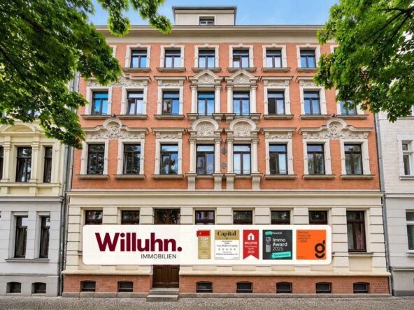 Historic red-brick building with ornate white decorative trim and a large Willuhn Immobilien storefront sign on the ground floor.