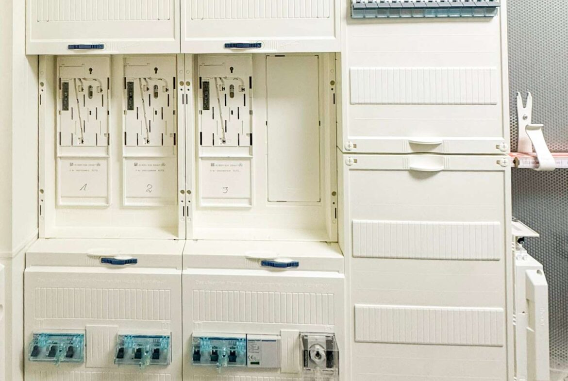 White electrical switchgear cabinets with multiple breakers and blue handles in a clean utility room.